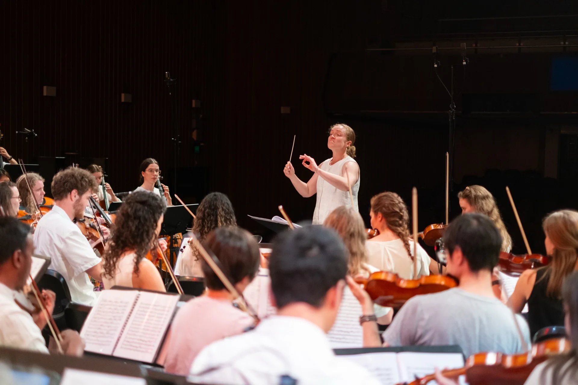 A conductor leading the Australian Christian Orchestra in rehearsal