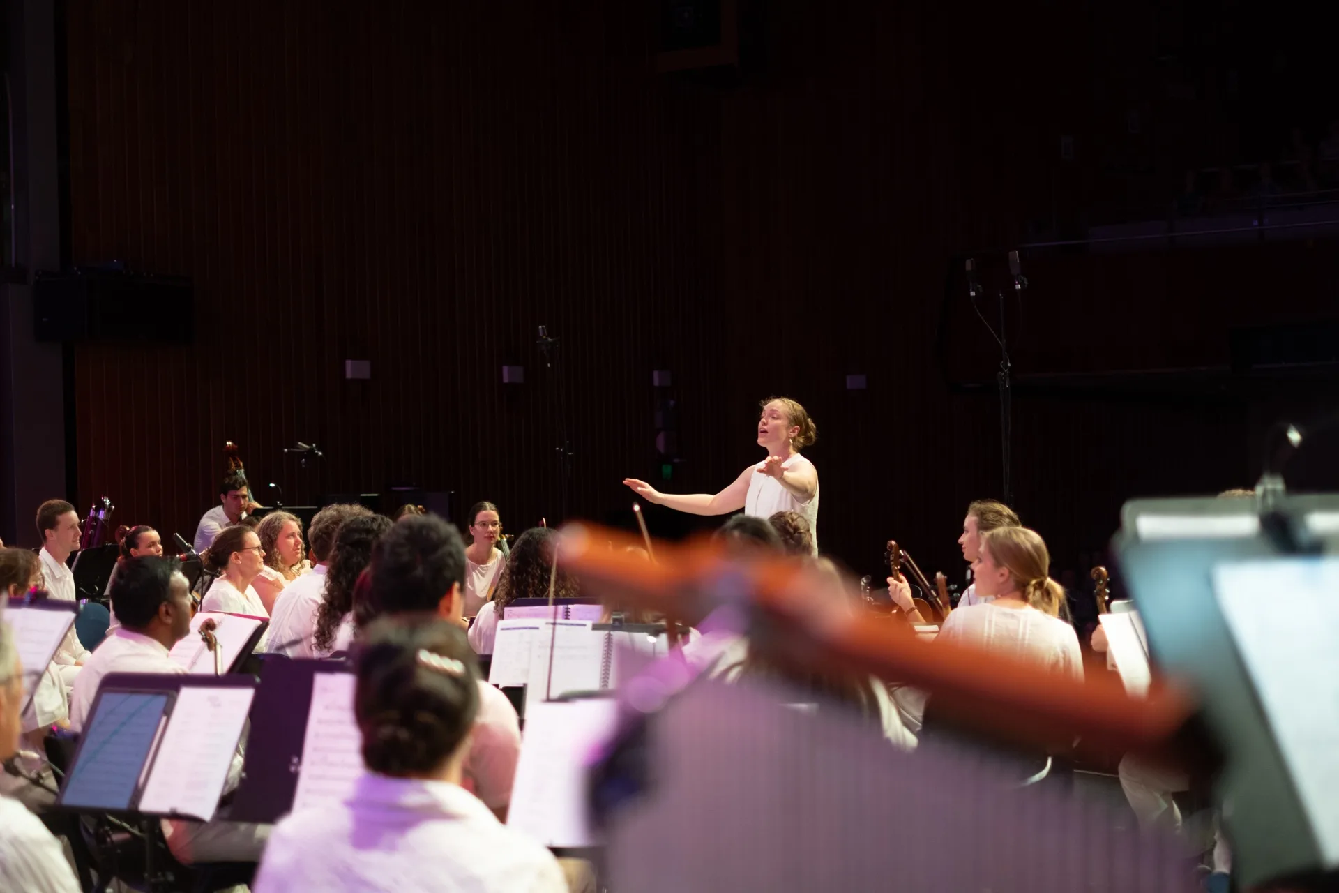 Conductor singing with arms outstretched leading the Australian Christian Orchestra