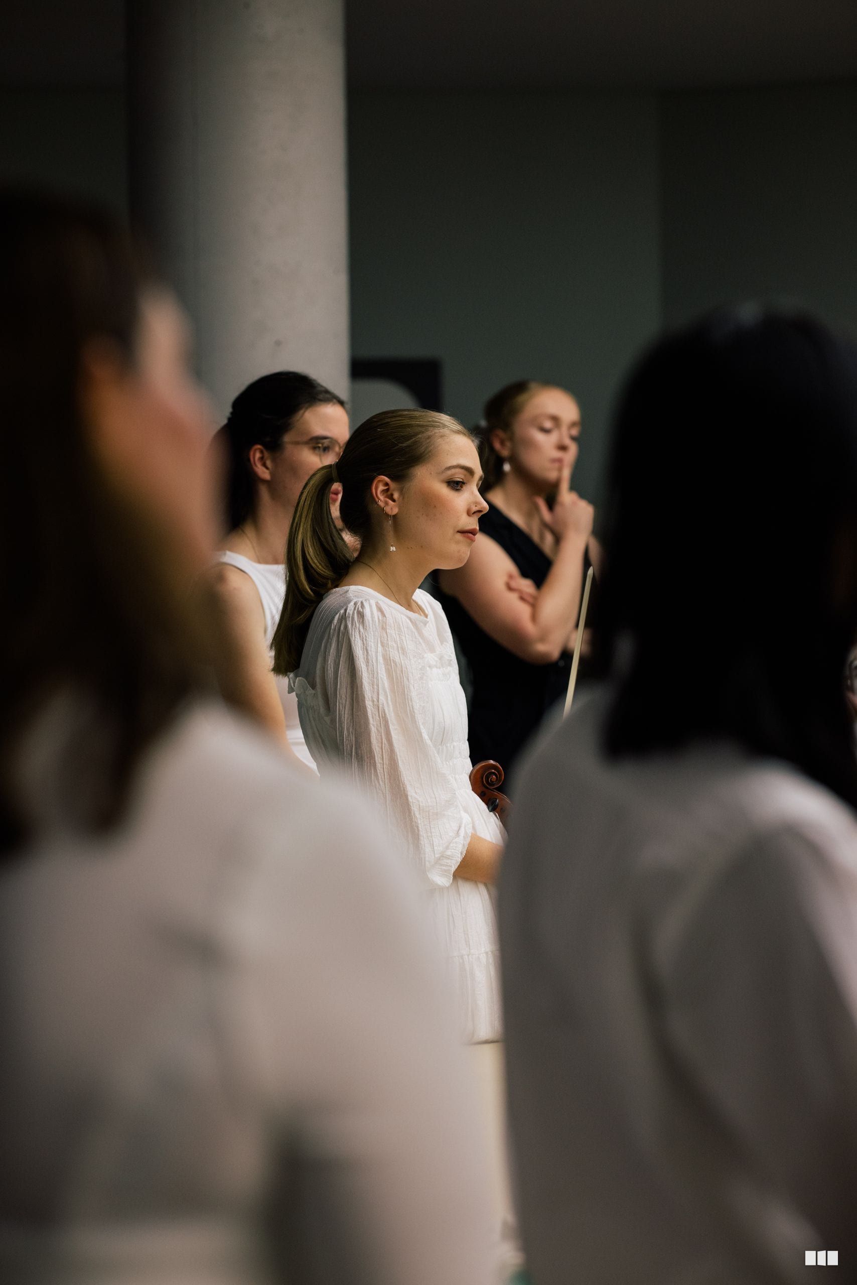 A choir member in white robes stands among other singers during a choral performance or rehearsal.