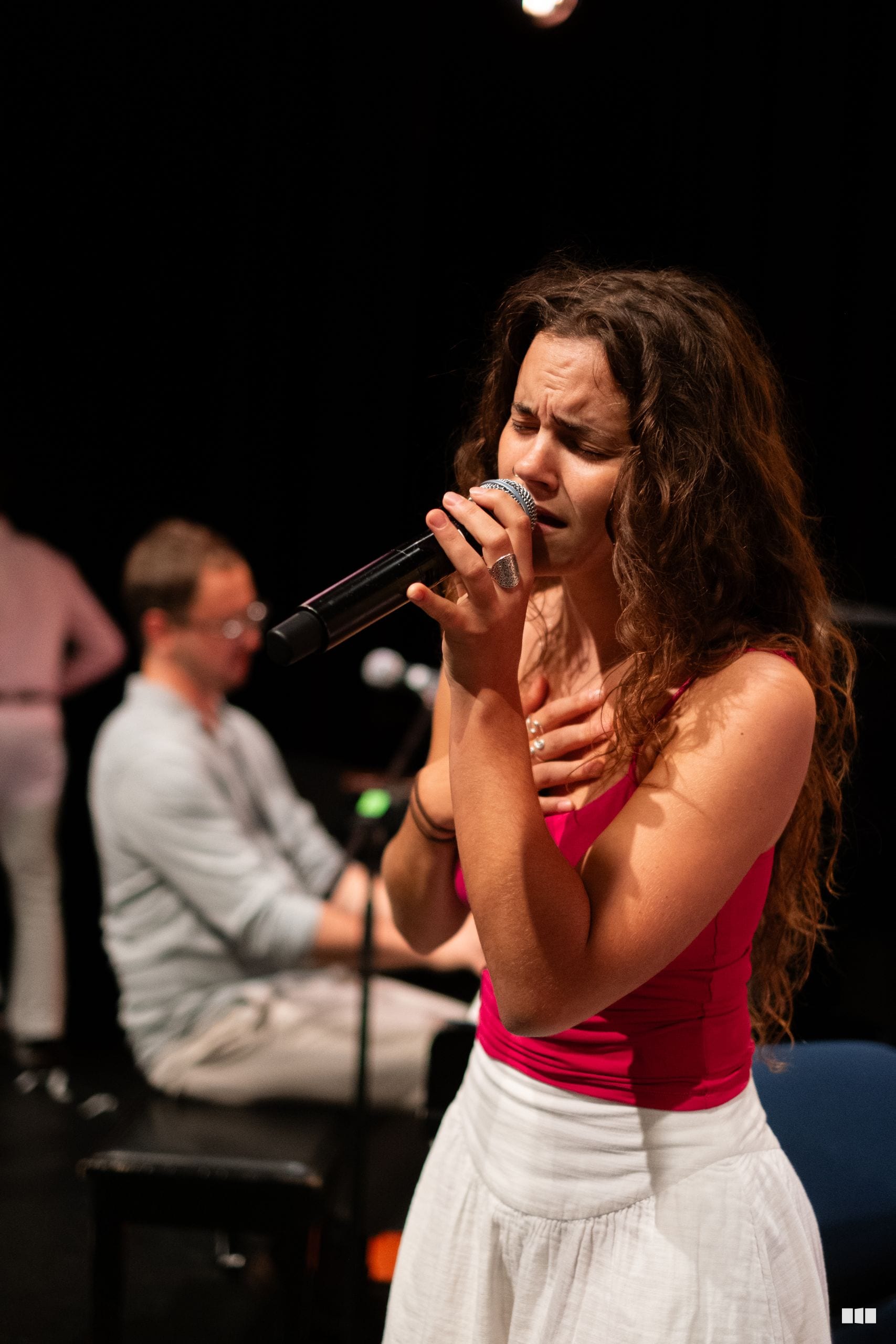 A female soloist performs passionately with a microphone on stage during an evening concert.
