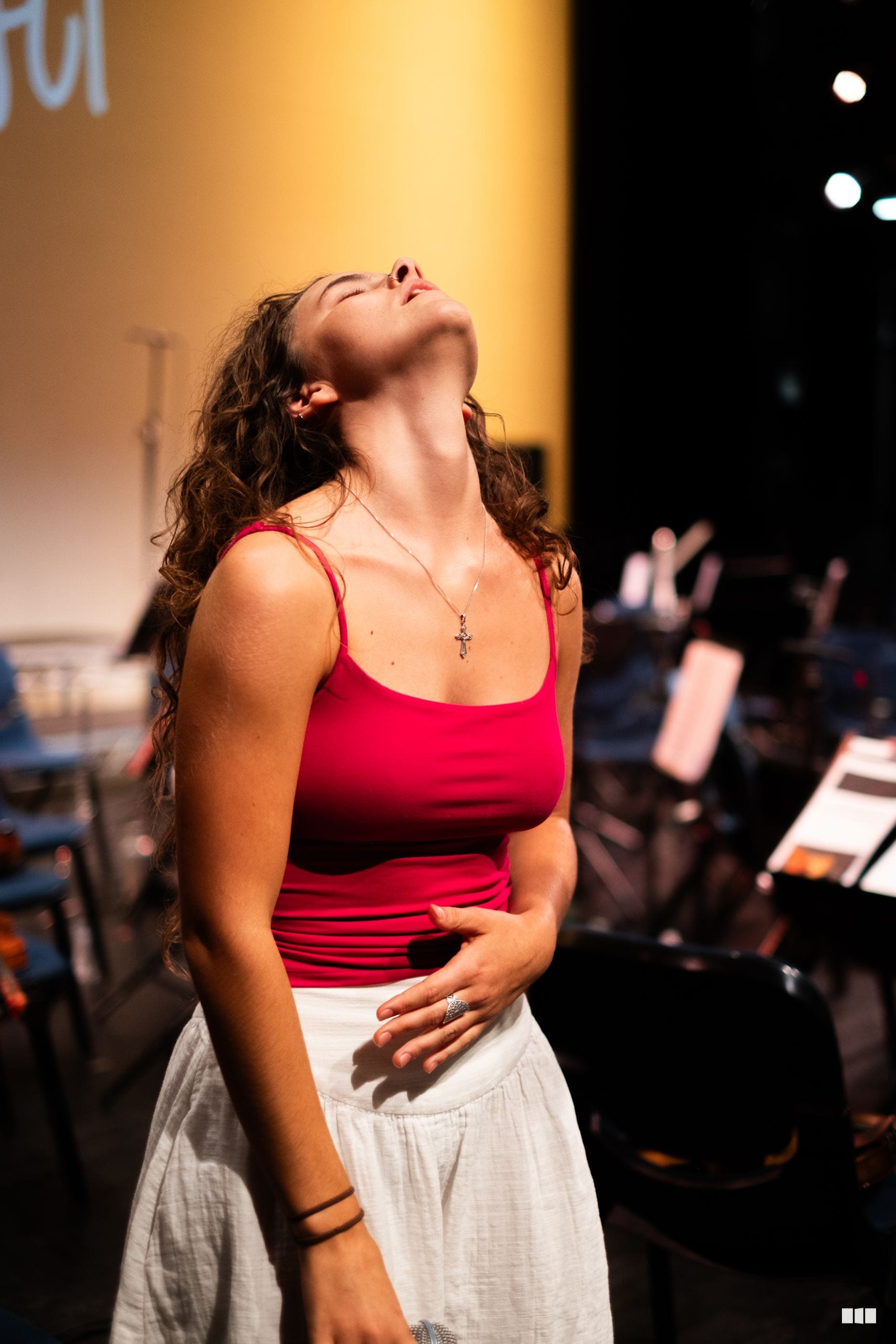 A soloist performs on stage with head tilted back in an emotional moment during a concert.