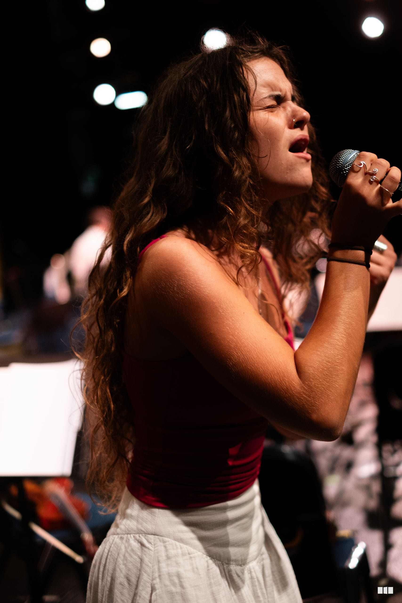 A female soloist performs passionately at the microphone during an evening concert performance.