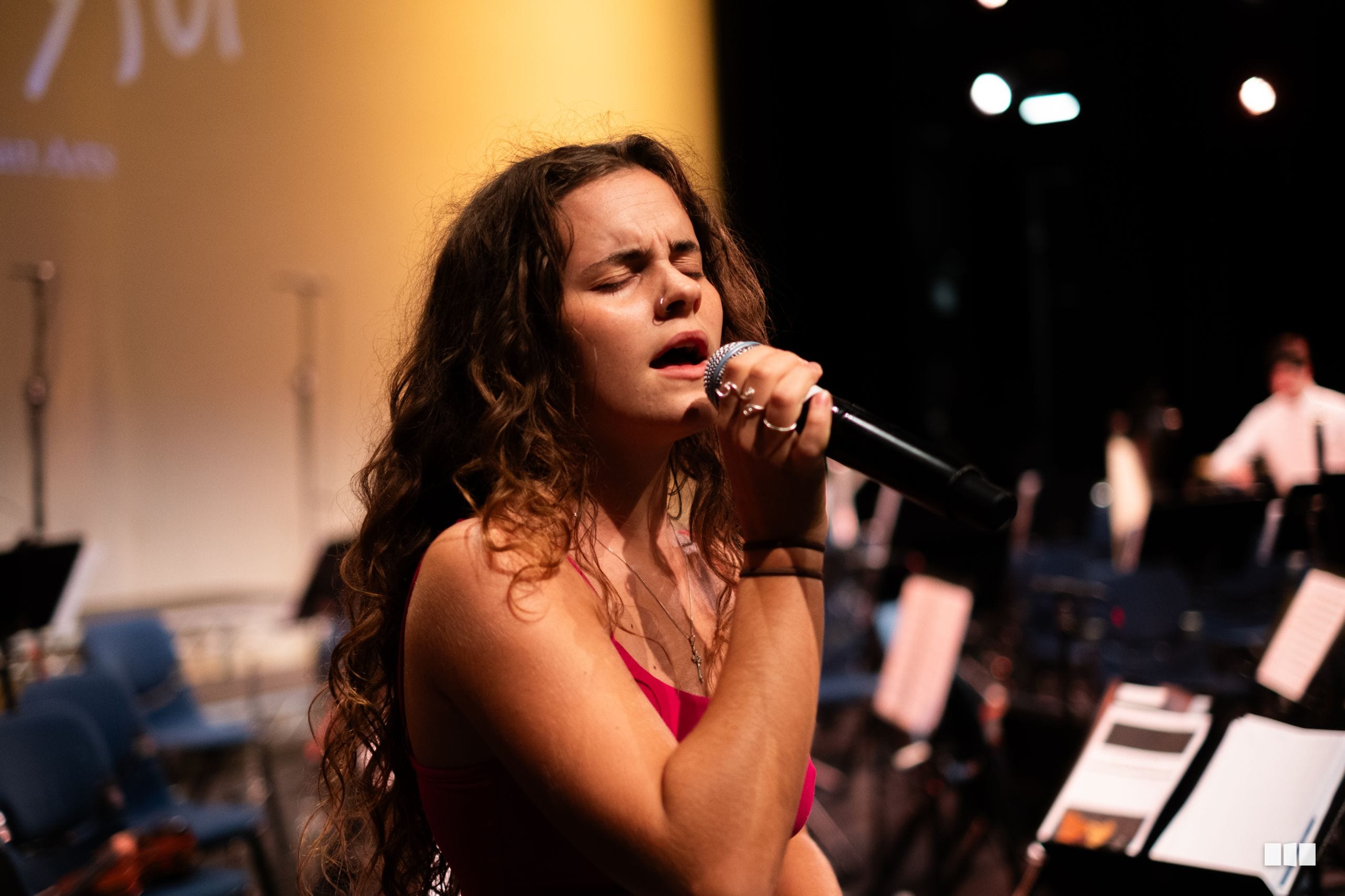 A female soloist performs passionately with microphone on stage during a choral performance.