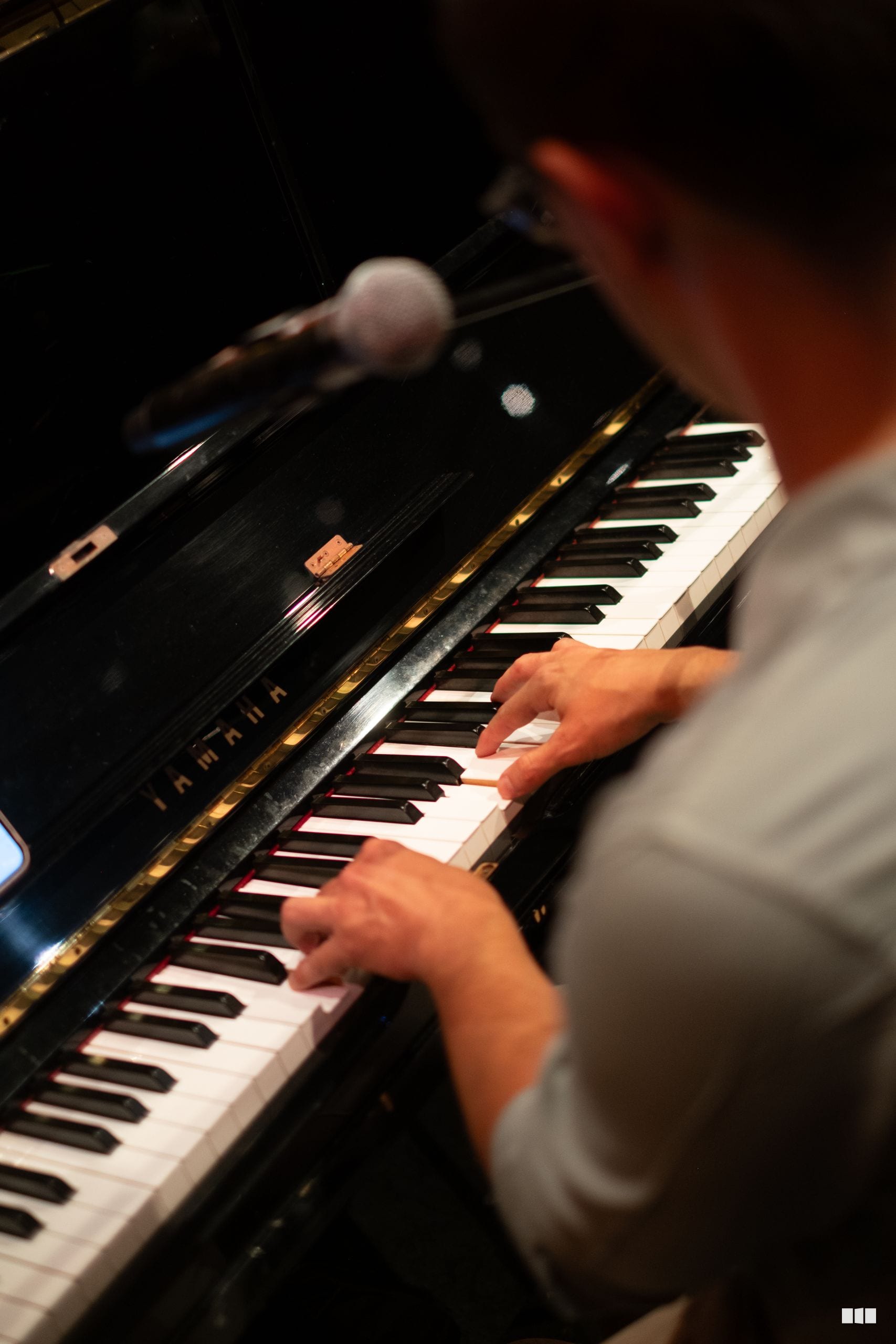 A young pianist's hands performing on a grand piano keyboard during a concert.