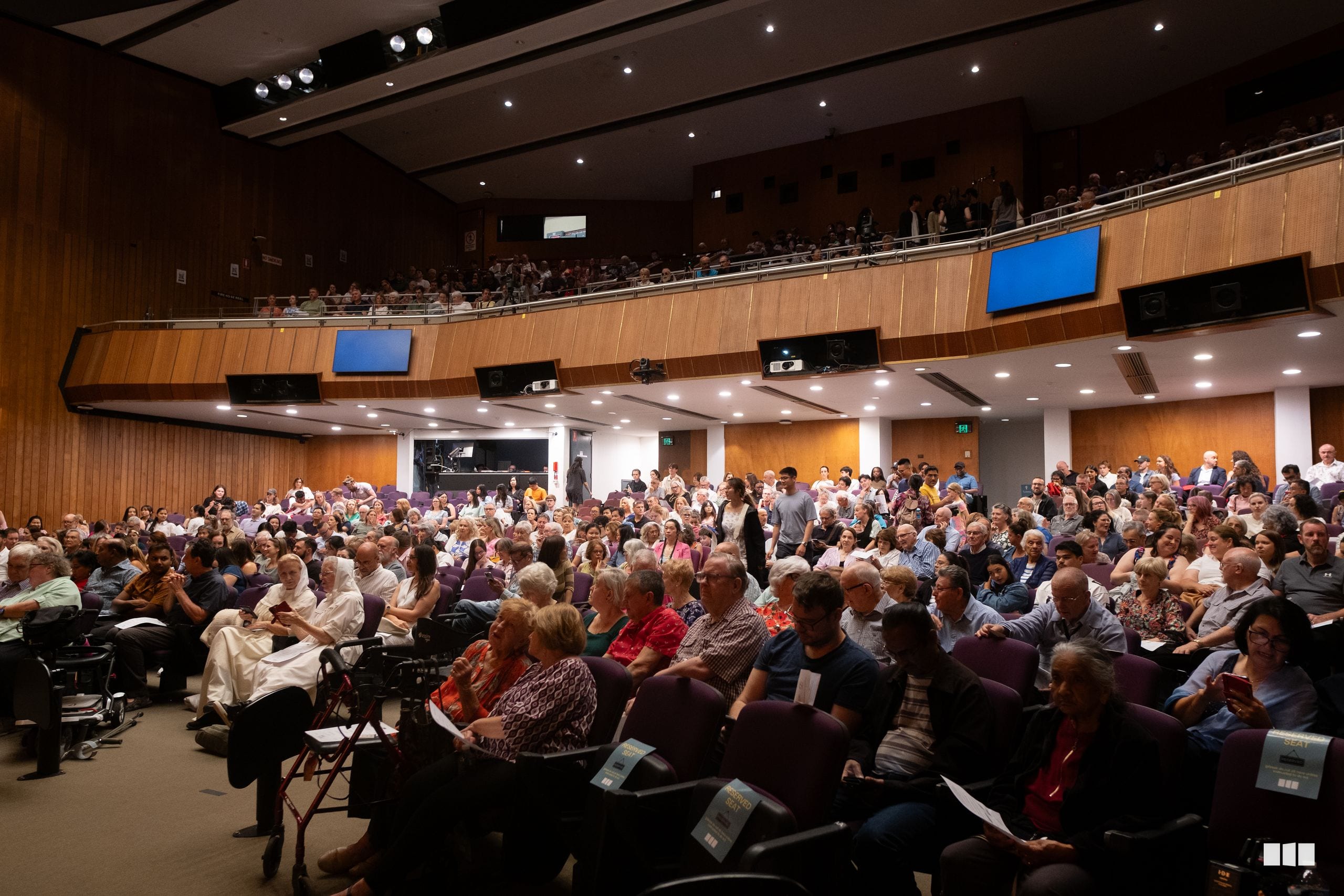 A large audience fills an auditorium during a community event at Australian Christian Arts.