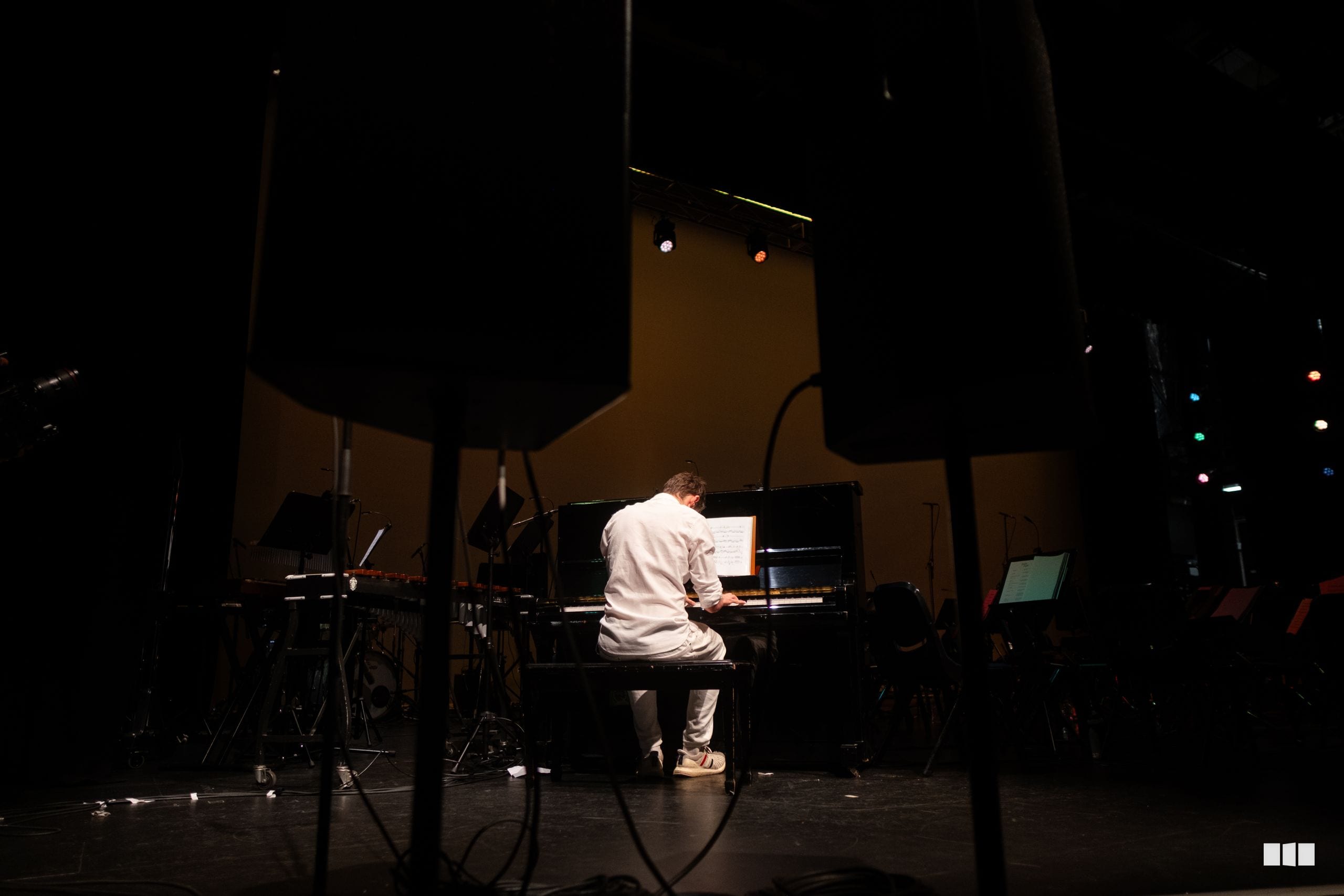 A pianist performs at the grand piano on stage during an evening concert.