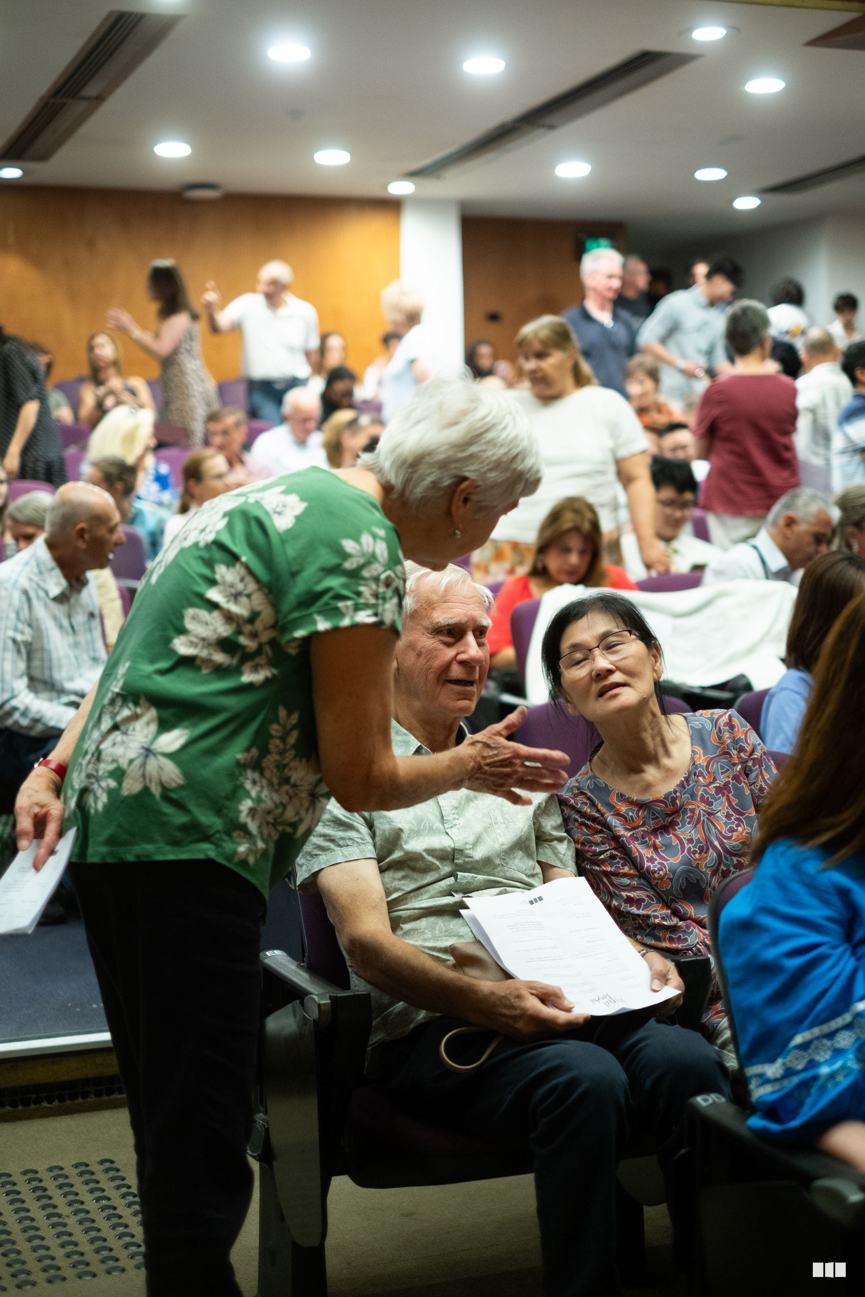 Congregation members interact and socialize during a community gathering in an indoor venue with modern lighting.