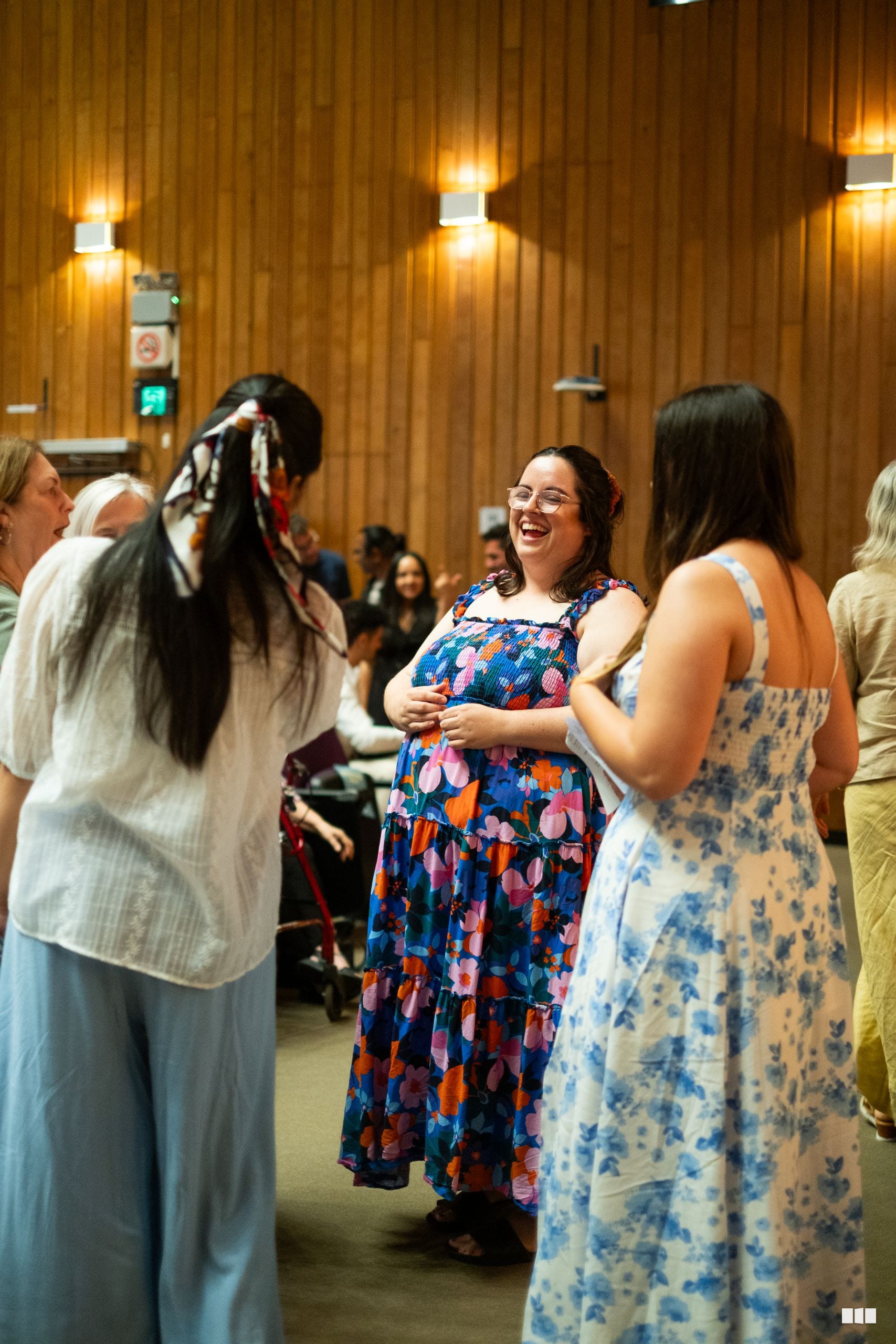 A group of people enjoy animated conversation and laughter at an indoor venue event.