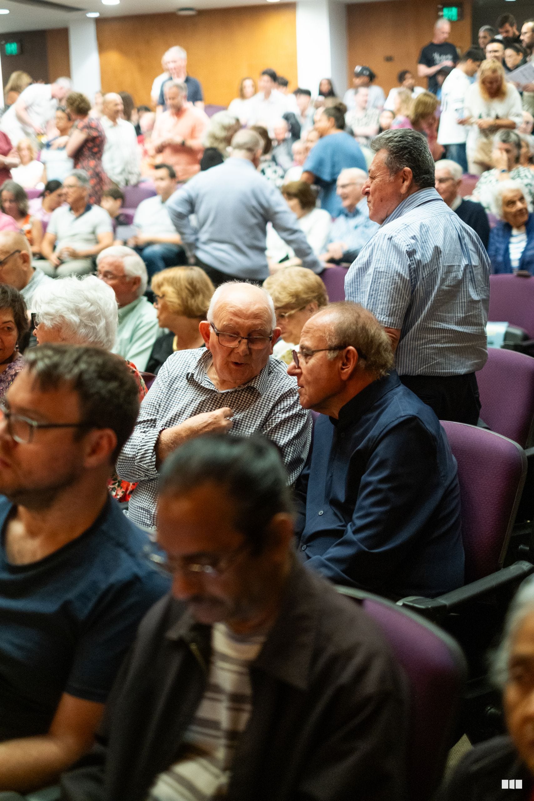 A diverse audience of primarily older adults and families gathered in a church hall for a community event.