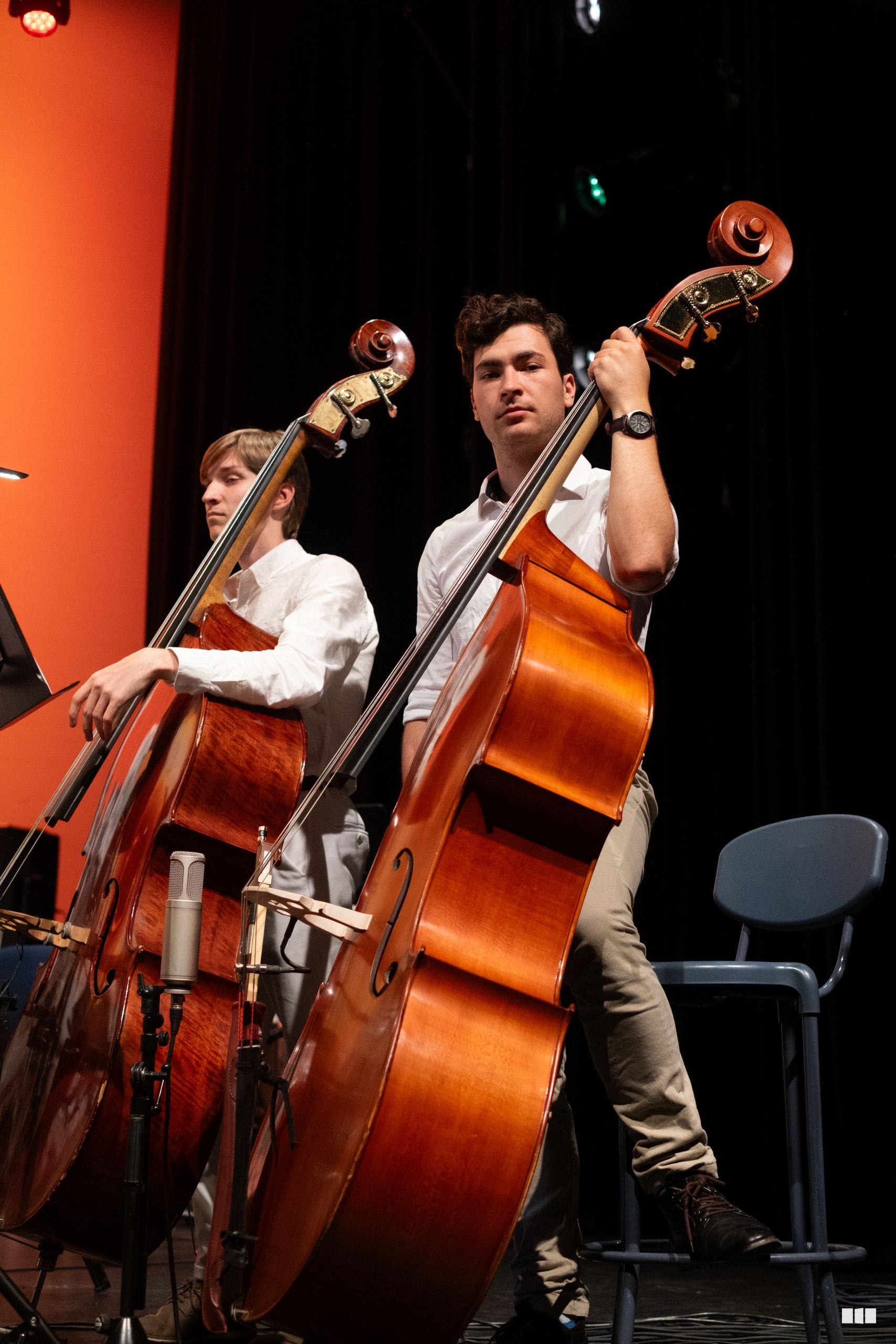 Two cellists perform together on stage during an orchestral concert.