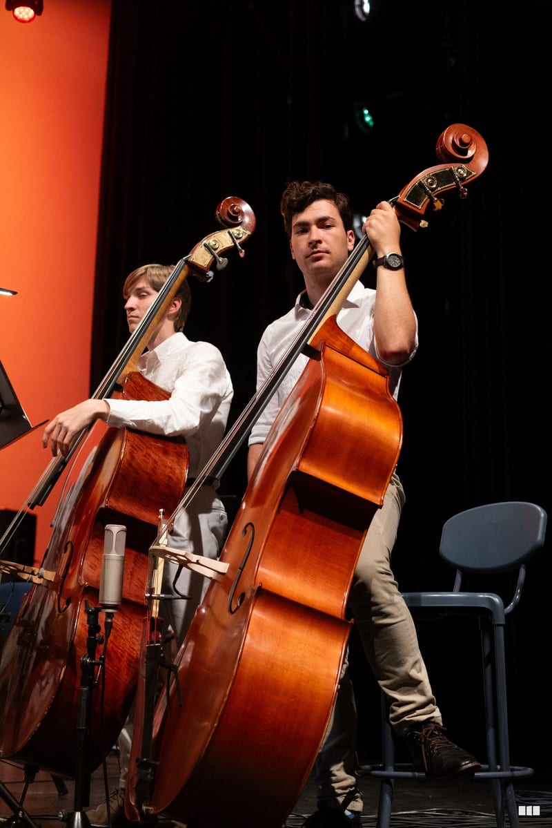 Two cellists perform together on stage during an orchestral concert.
