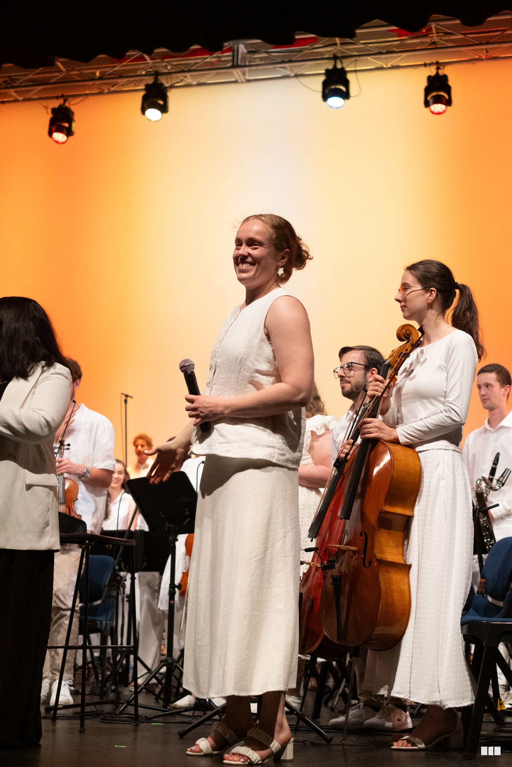 A conductor addresses the orchestra and choir members on stage during a performance.