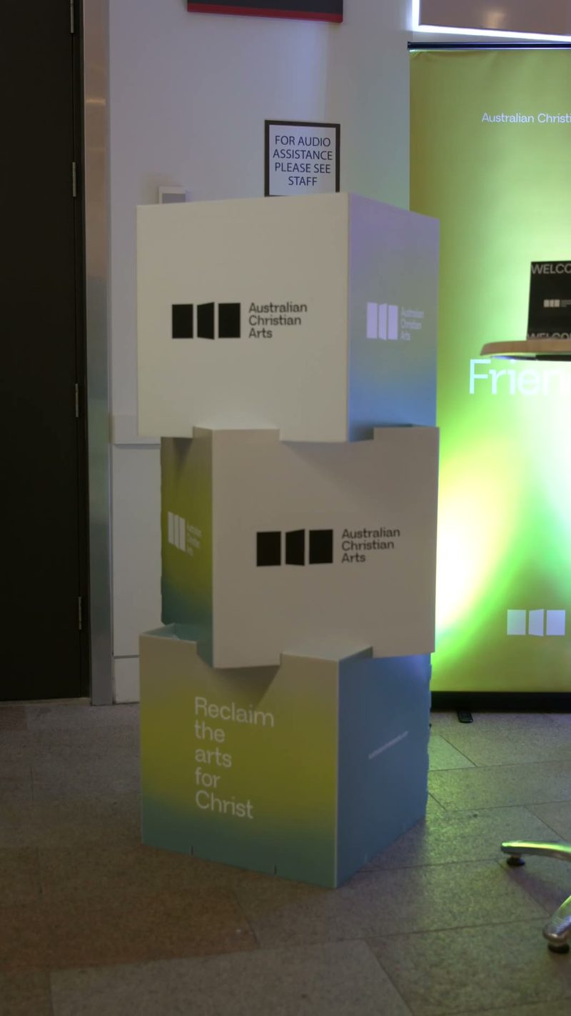 Australian Christian Arts branded display boxes stacked in the venue entrance area promoting their mission to reclaim the arts for Christ.