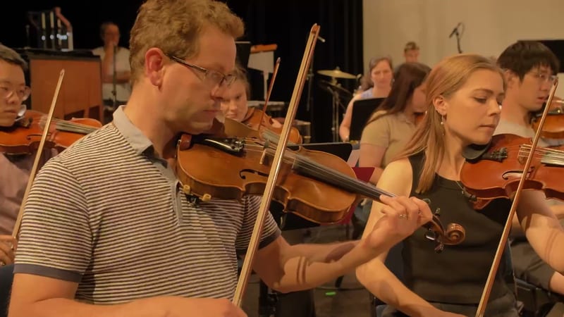 Violinists performing together during an orchestral rehearsal or performance.