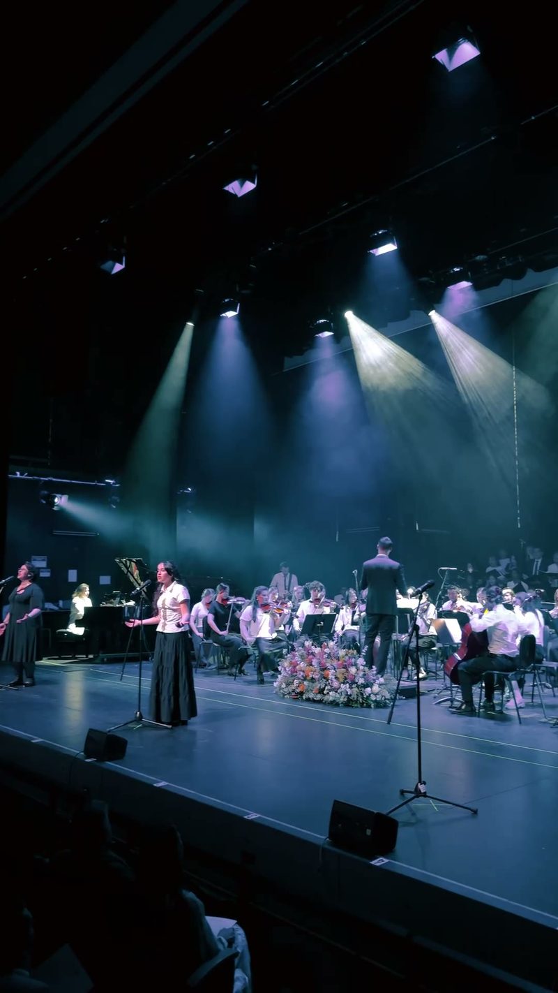 A performance featuring soloists and an orchestra on stage.