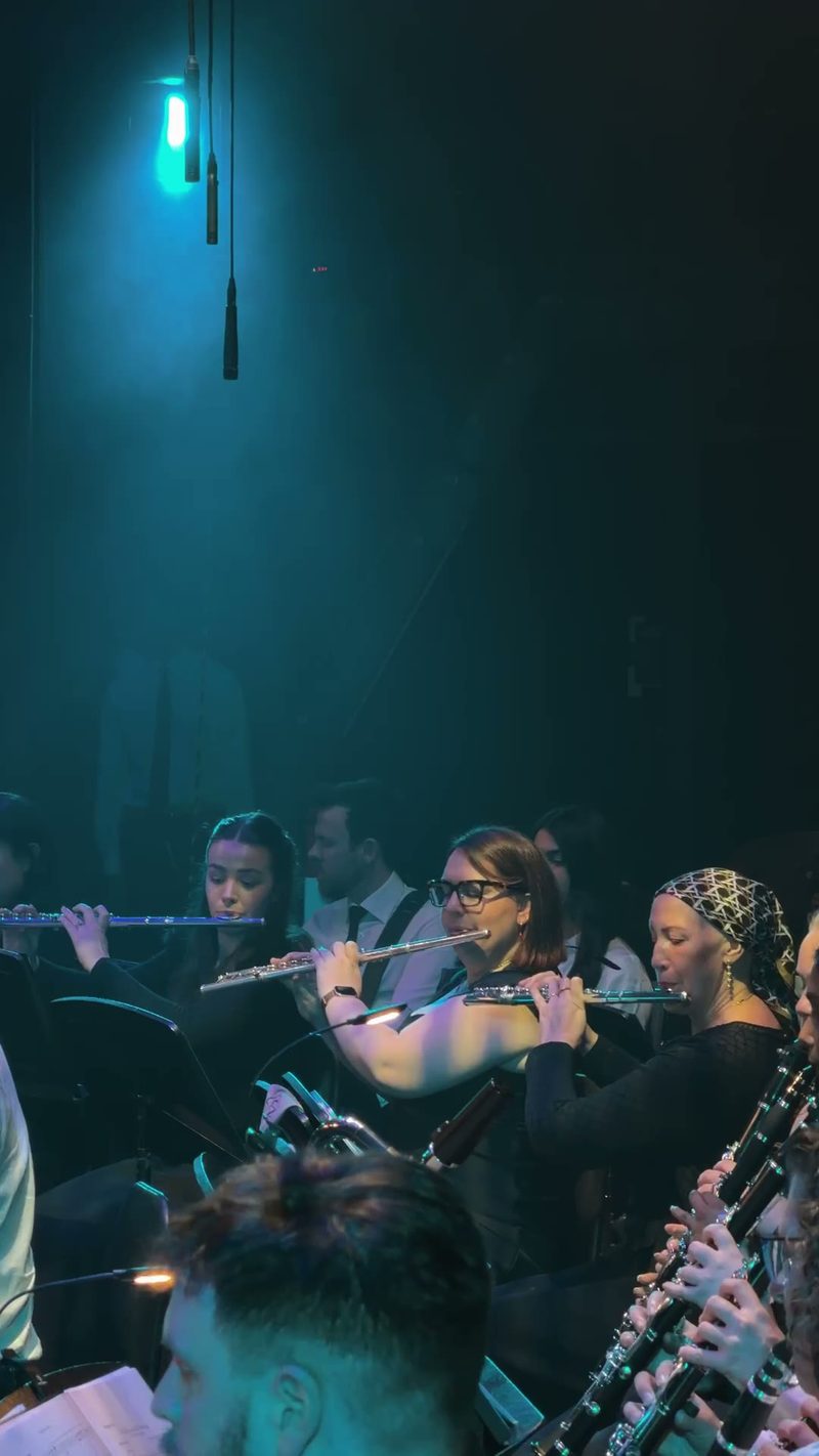 Musicians performing with flutes in a dimly lit setting.