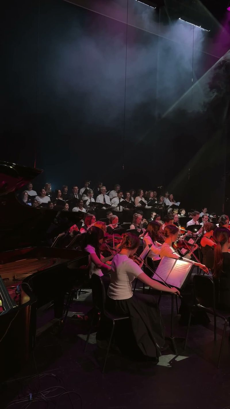 A performance featuring musicians and a choir on stage.