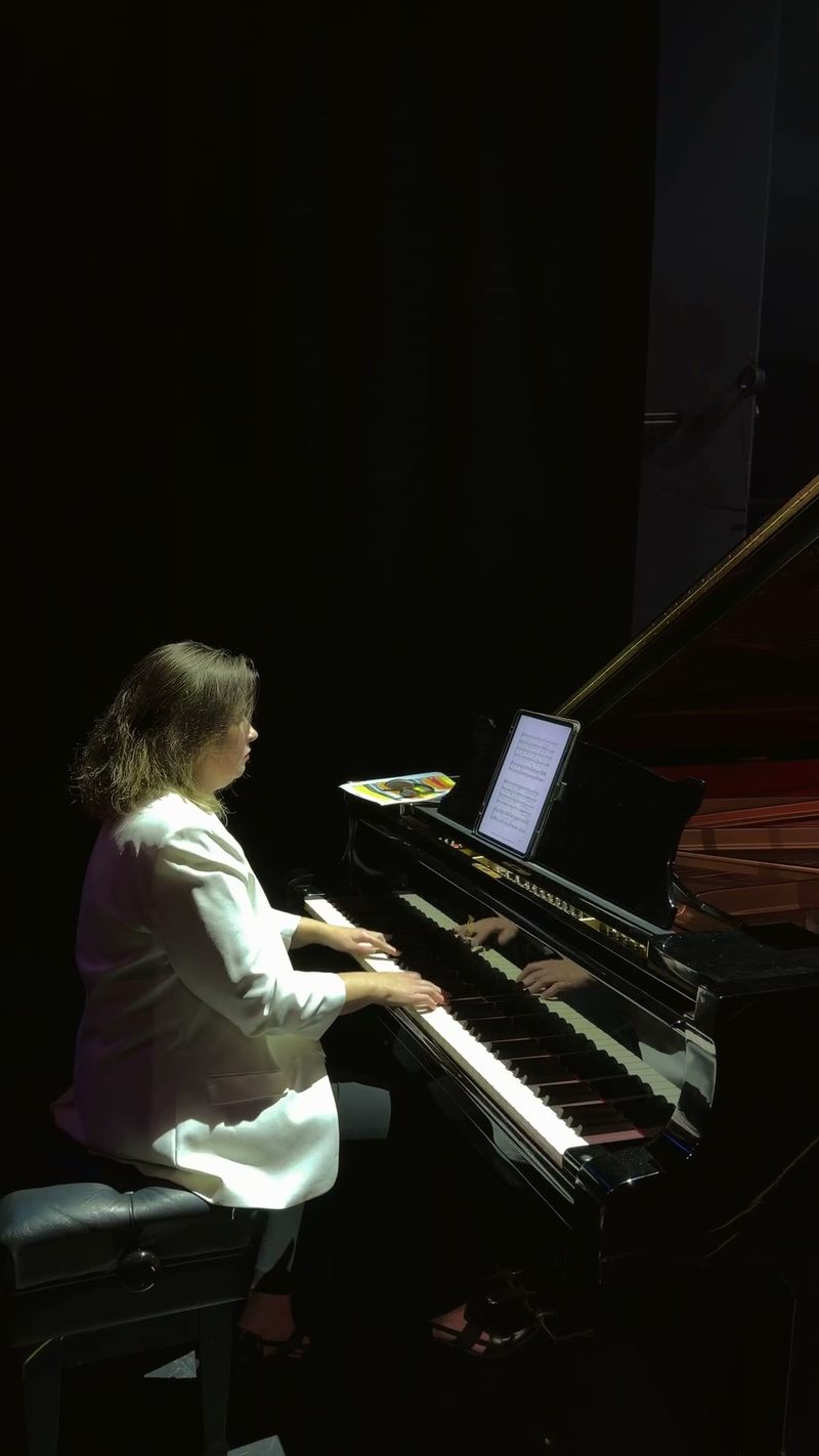 A pianist performing on stage under spotlight.