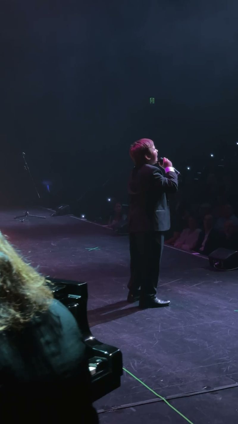 A young performer singing passionately on stage.