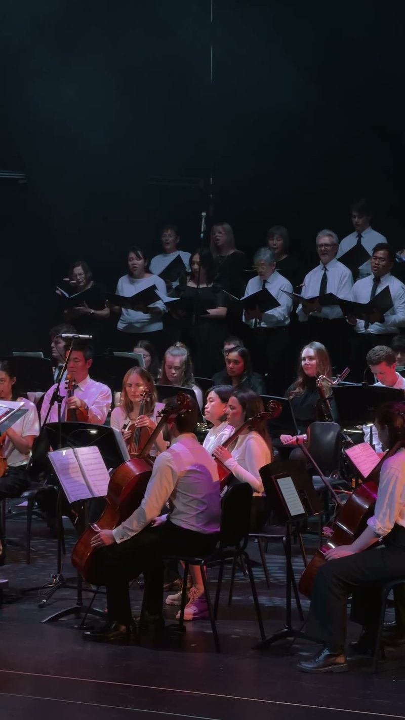 A symphony orchestra and choir performing on stage.