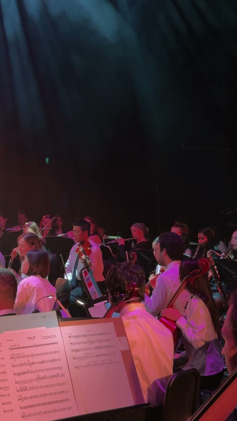 An orchestra performing on stage with musicians in formal attire.