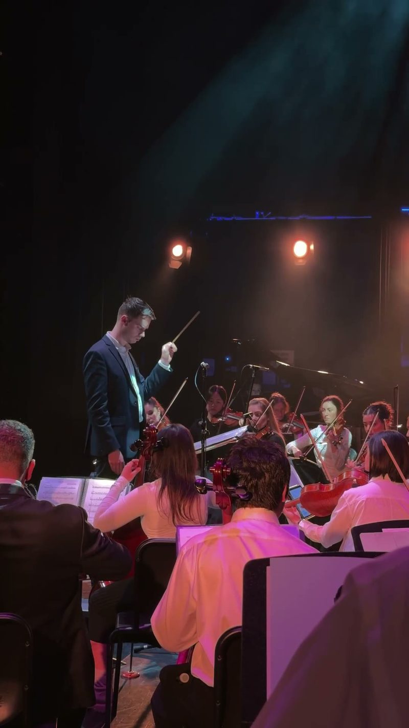 A conductor leads a symphony orchestra during a performance.