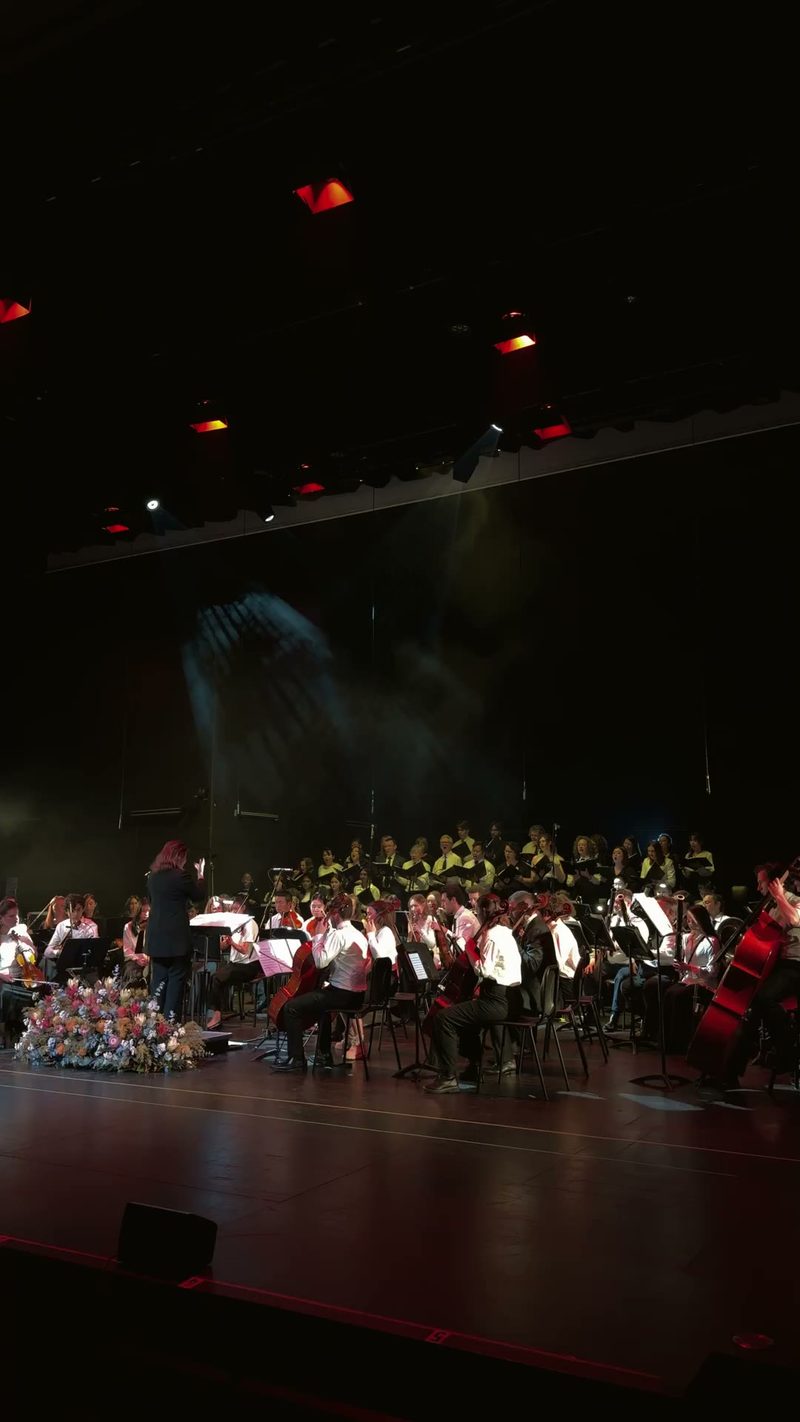 An orchestra and choir performing on stage.