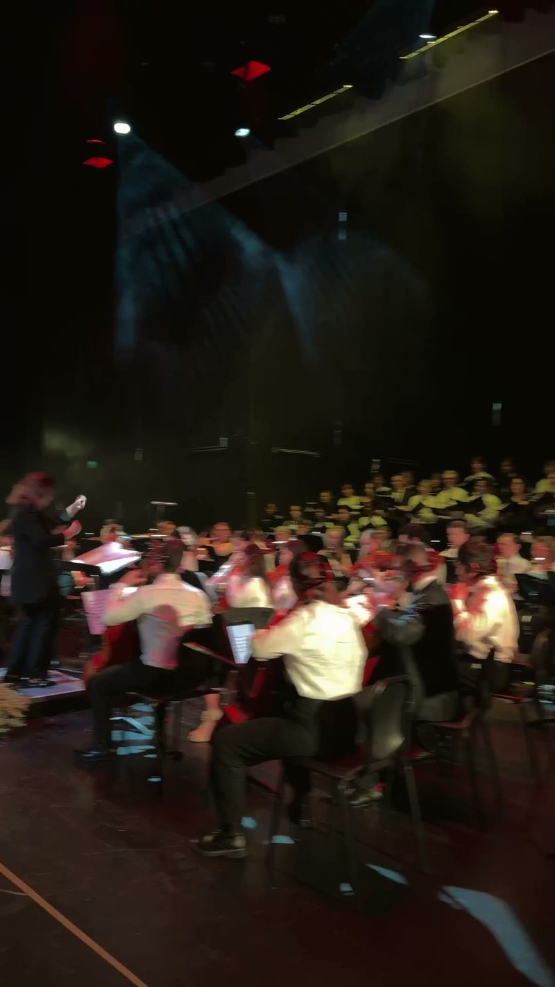 A choir performs alongside an orchestra on stage.