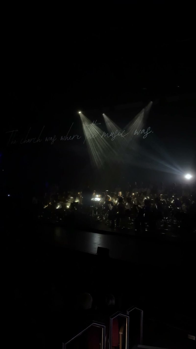 A symphony orchestra performing under dramatic lighting.
