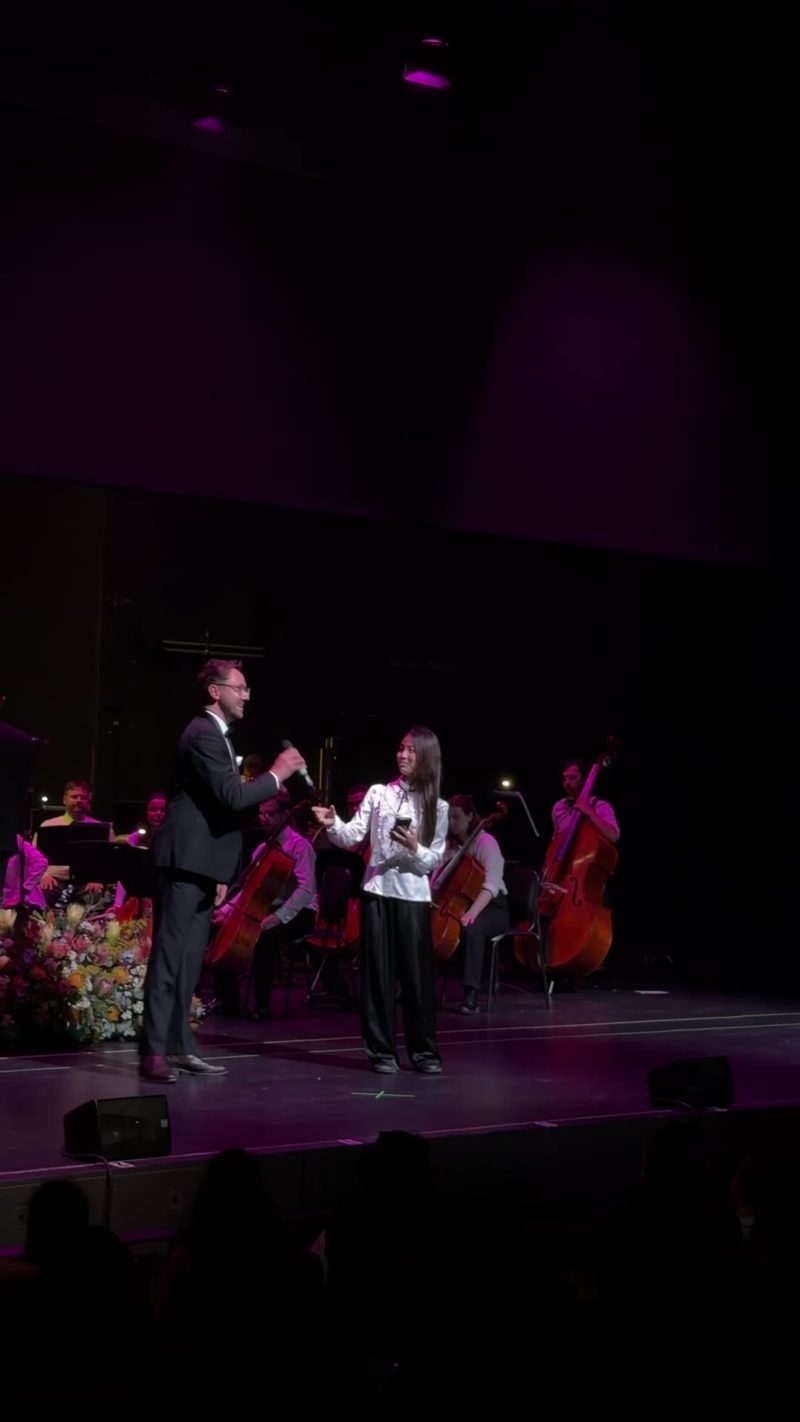 A performance featuring a soloist with an orchestra in the background.