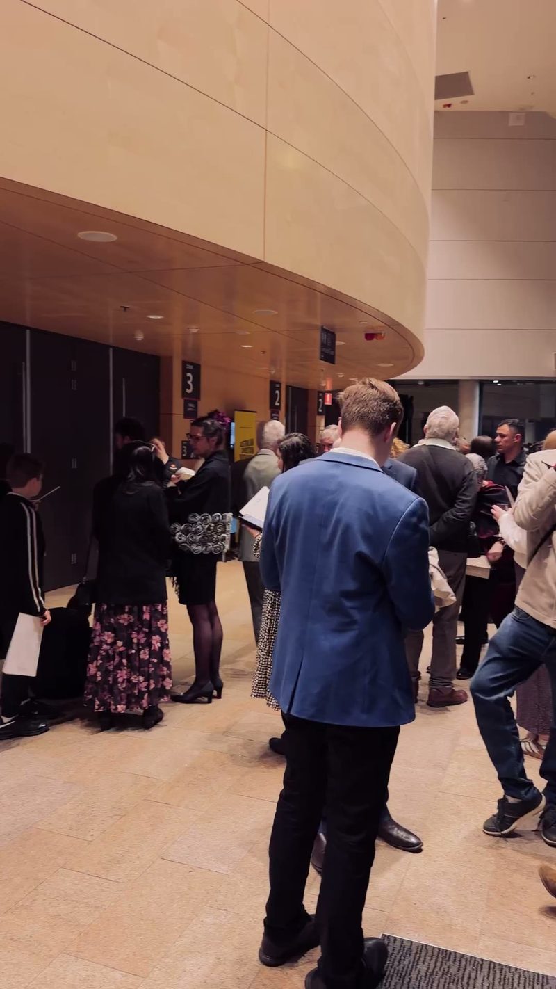 A group of people gathering in a lobby area, likely waiting for a performance to start.