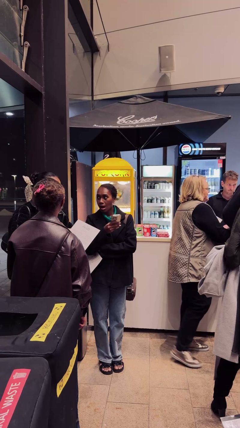 A group of people gathered near a snack stand at an event, discussing something while enjoying snacks and drinks.