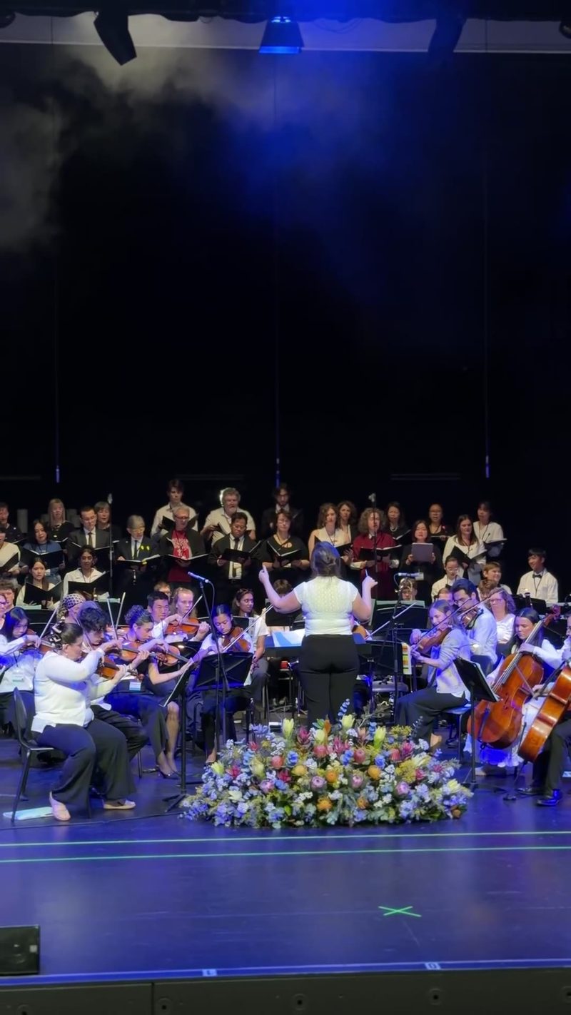 A conductor leads a symphony orchestra and choir during a performance.