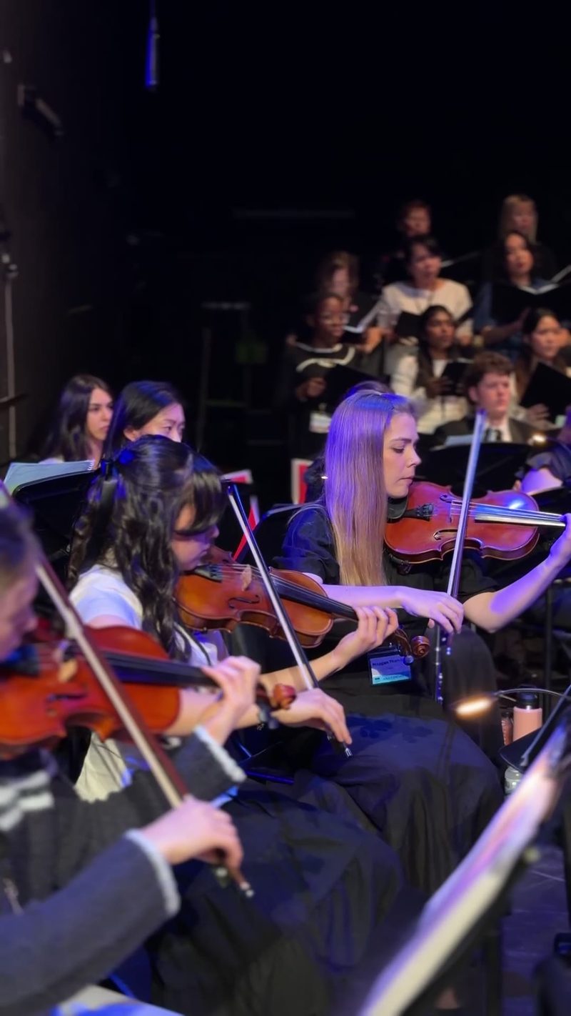 A group of young musicians performing together with violins.