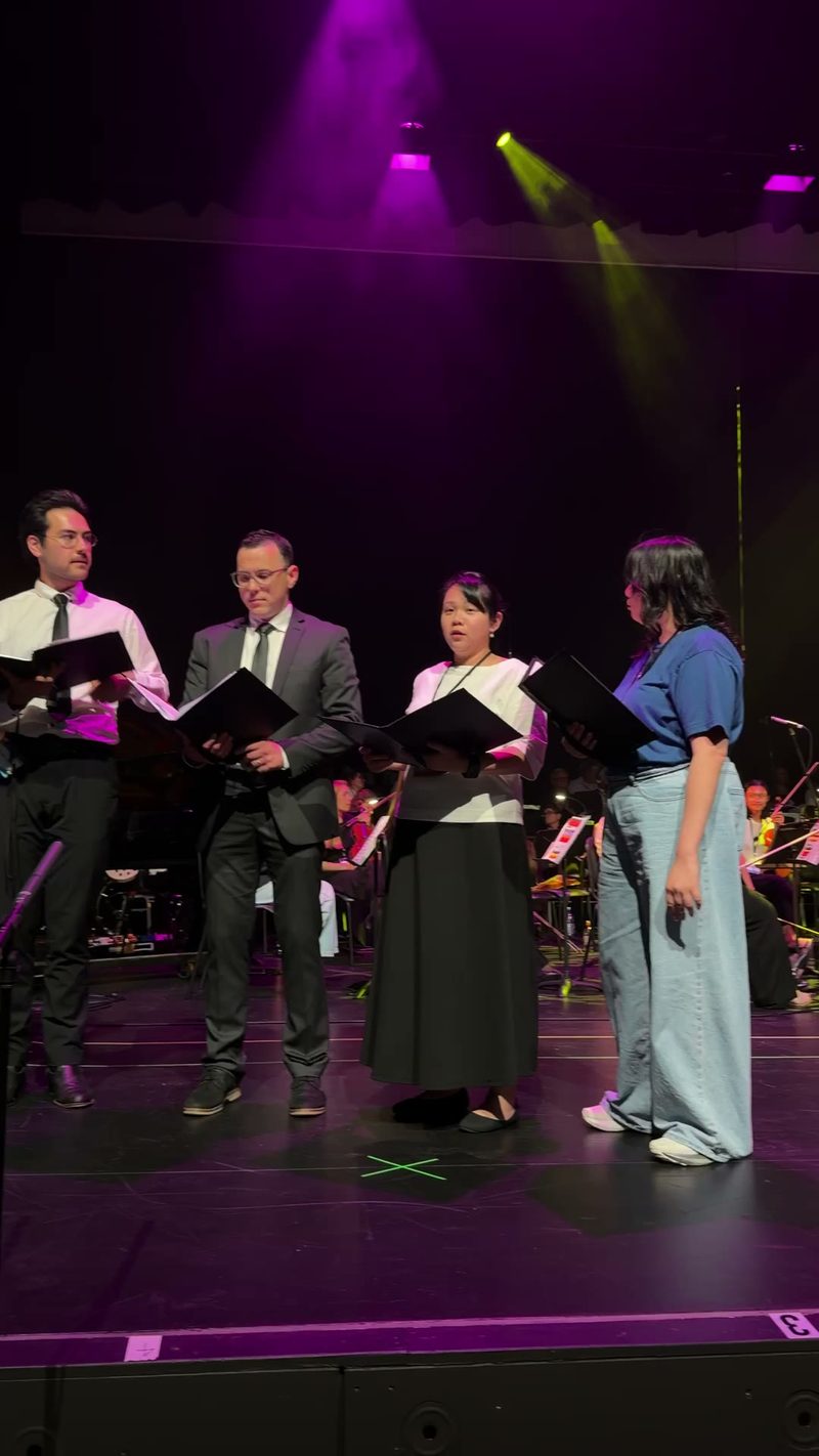 A choir performs on stage under colorful lights.