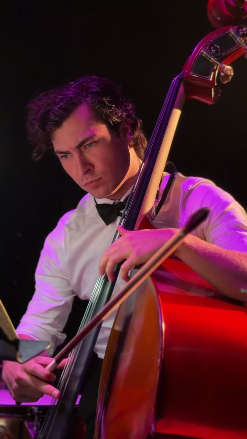 A focused young cellist performs in a symphony setting.