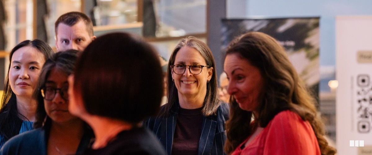 A group of adults smile and chat together at what appears to be a professional networking or arts event