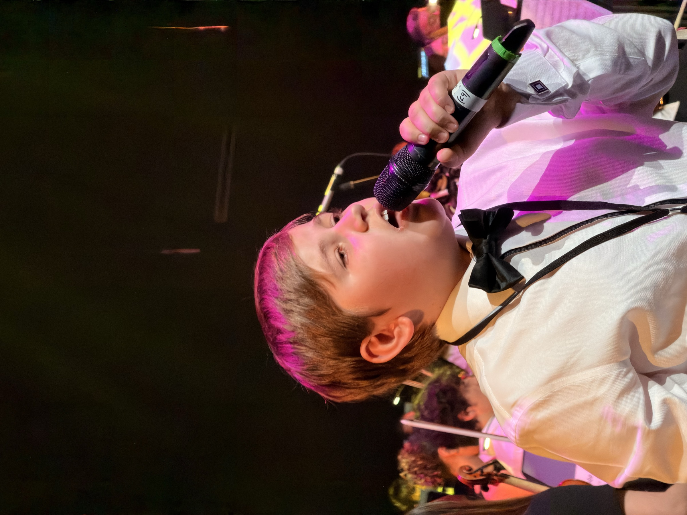 A youth vocalist performing under stage lights at the Australian Christian Proms.